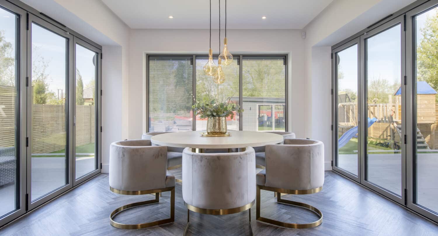 Modern dining room extension with round table and chairs featuring aluminum bi-folding floors