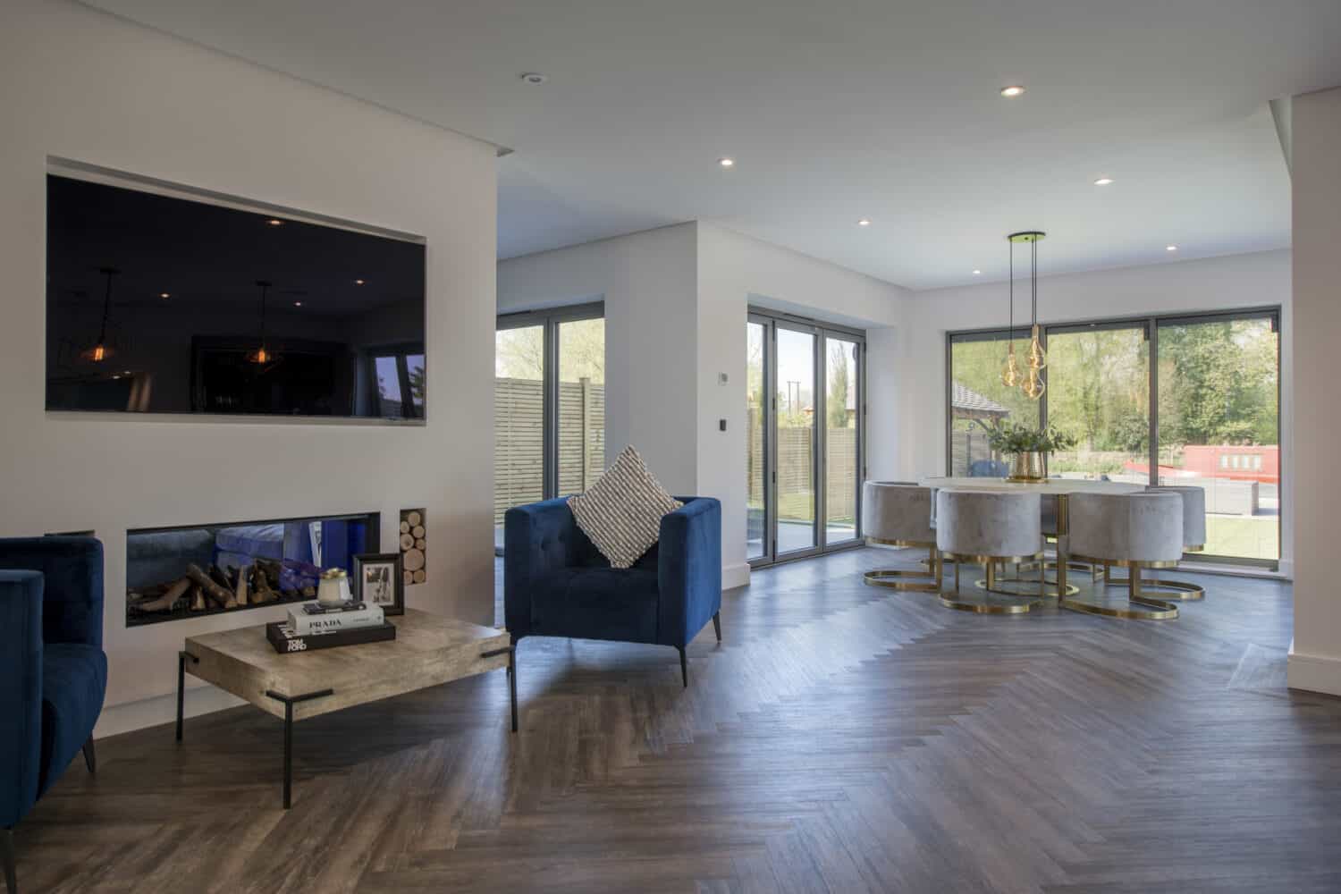 Home entertainment space with bespoke aluminium sliding windows leading to garden