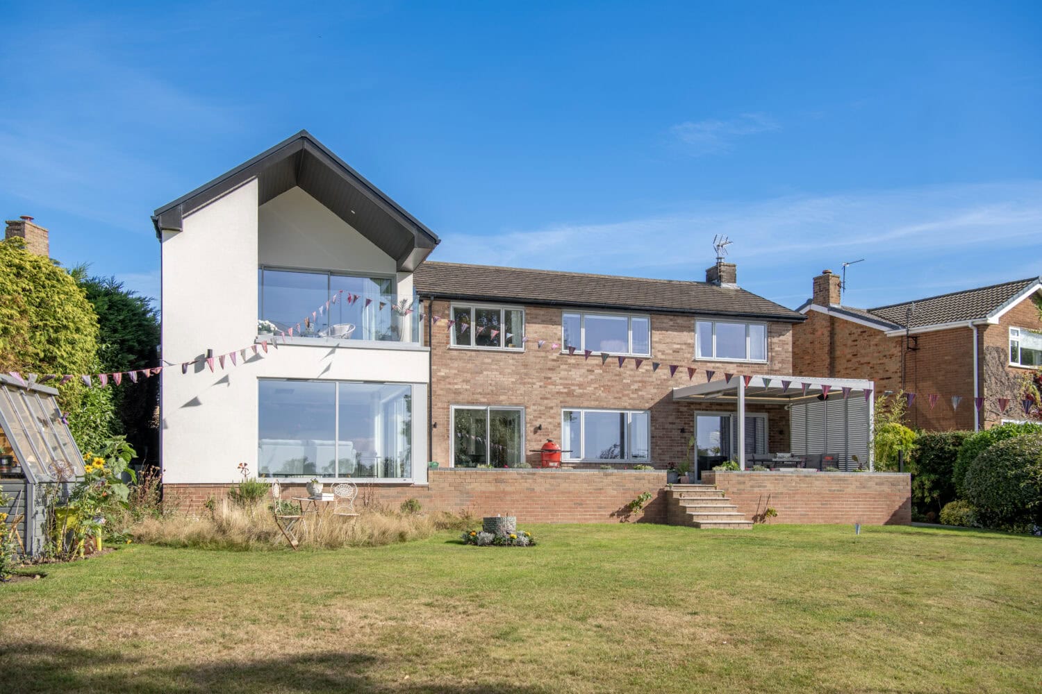 Bi-folding doors installed at Firs Drive, Harrogate, showcasing seamless indoor-outdoor living with large glass panels and sleek aluminium frames.
