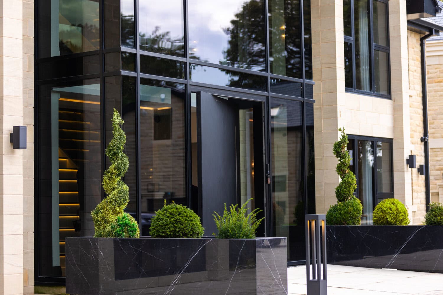 Elegant pivot doors with sleek black frames and large glass panels, enhancing contemporary home entrances with a sophisticated look.