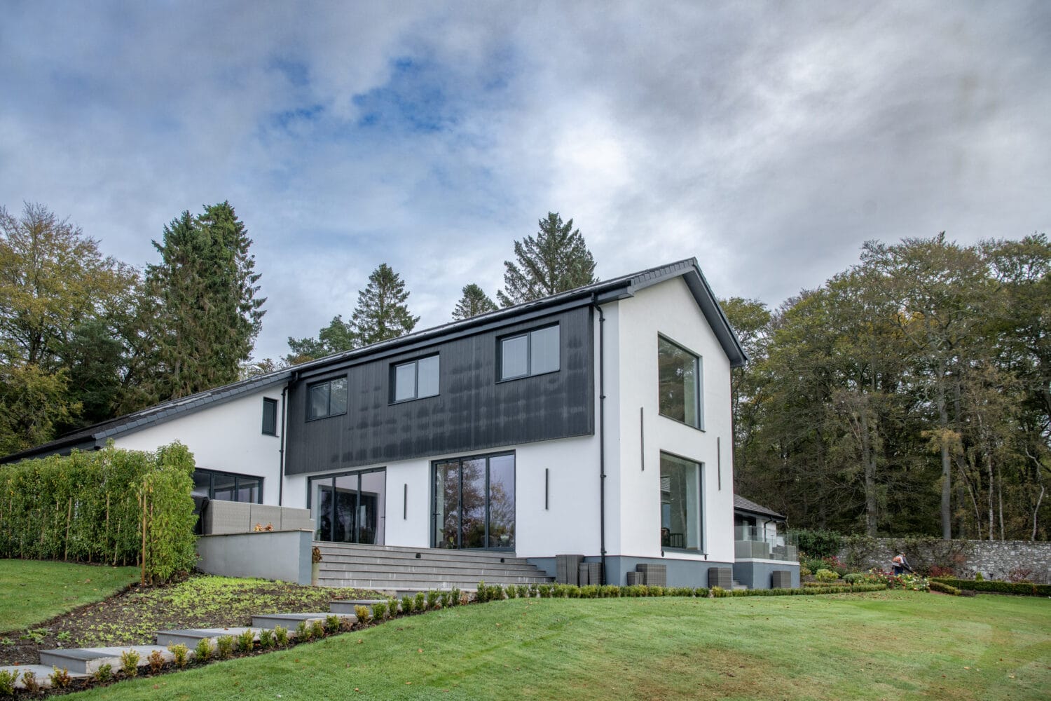 Contemporary garden house featuring large bi-folding doors for seamless indoor-outdoor living, set in Aberdeen with lush greenery and scenic surroundings.