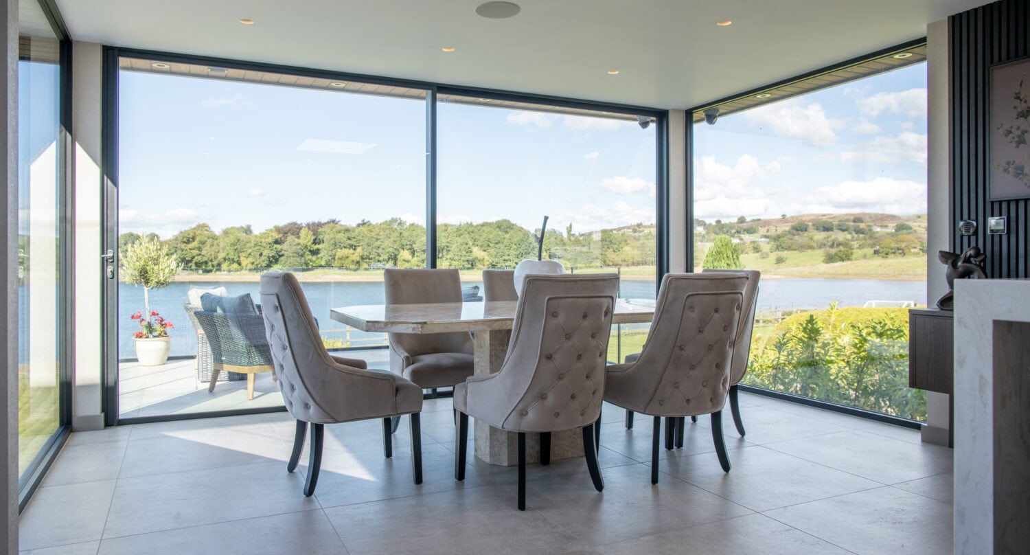 Elegant indoor dining area with large bi-folding doors opening to scenic outdoor views.