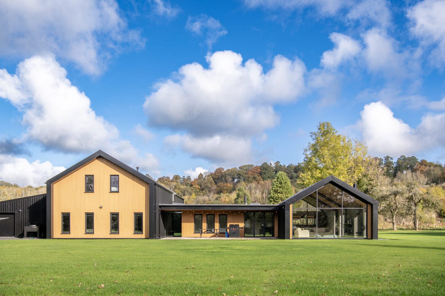 Elegant Orchard Farm property featuring large bi-folding doors that open to expansive green lawns, enhancing natural light and outdoor views. Perfect for contemporary rural homes.