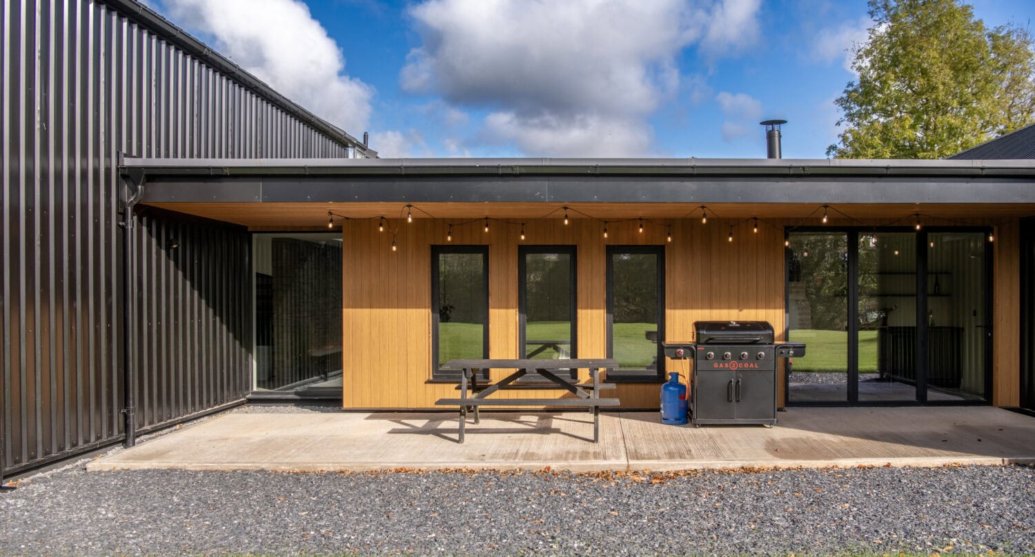 Contemporary bi-folding doors at Orchard Farm, Crossford, showcasing seamless indoor-outdoor living with large glass panels and sleek black frames.