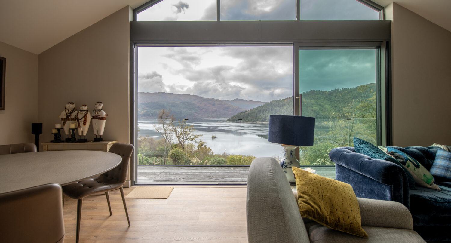 Elegant bi-folding doors opening to scenic lake views at Norse Lodge, Helensburgh, showcasing modern design and seamless indoor-outdoor living.