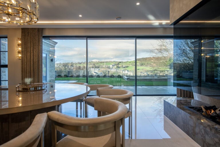 XP Glide bi-folding doors opening to a scenic landscape, showcasing sleek design and large glass panels for seamless indoor-outdoor living.