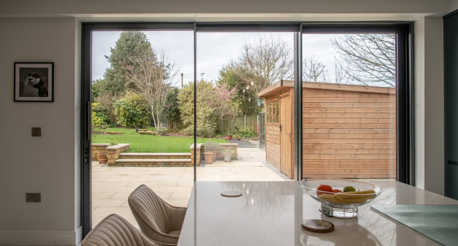 Modern Chapel Grove home with large bi-folding doors opening to a lush garden, showcasing stylish and functional glazing solutions for seamless indoor-outdoor living.