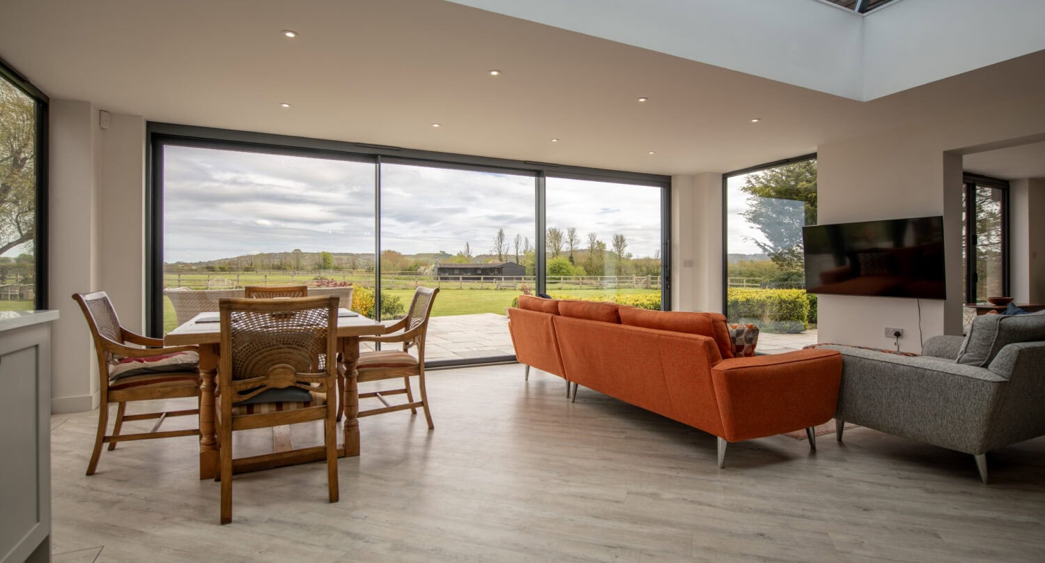 Large glass sliding bi-fold doors opening to a garden, providing natural light and seamless indoor-outdoor living. Perfect for contemporary home designs.