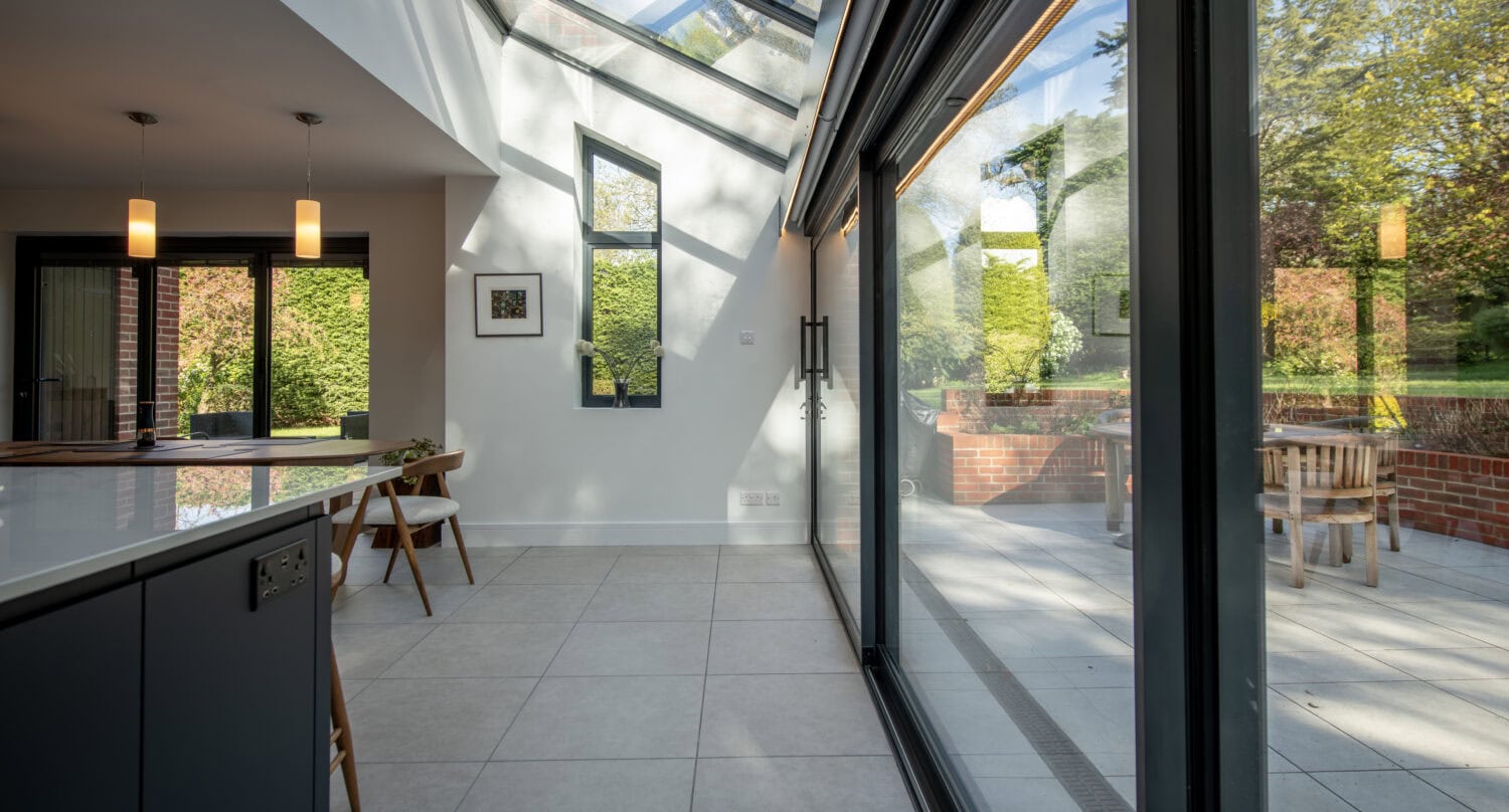 Modern sliding bi-fold doors opening to a bright outdoor patio, enhancing natural light and indoor-outdoor living. Perfect for contemporary home designs.