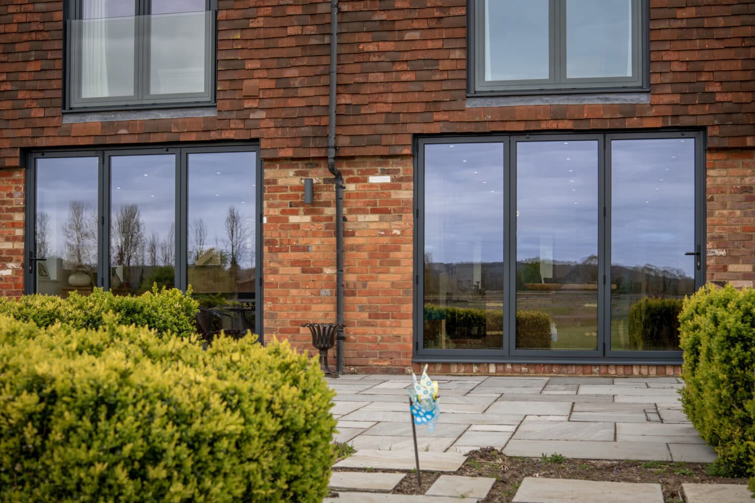Modern black sliding bi-fold doors installed in a brick house, providing seamless indoor-outdoor living space and enhancing natural light.