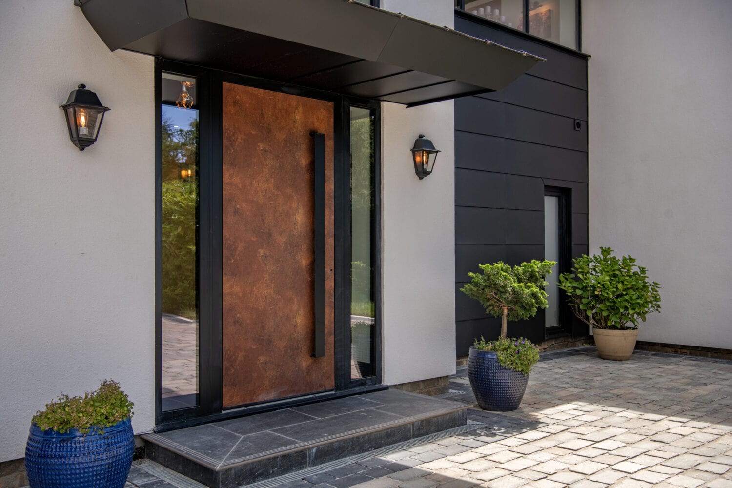 Contemporary entrance with bi-folding doors, stylish black and rust finish, and outdoor lighting, ideal for modern homes.