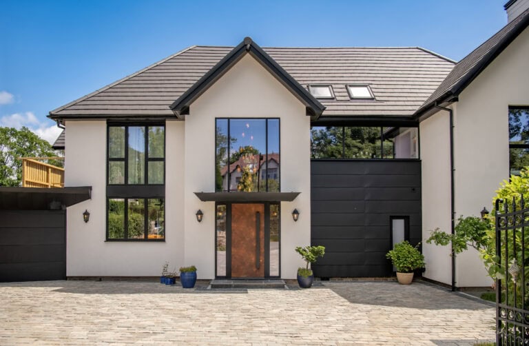 Modern house featuring large black bi-folding doors and expansive windows, showcasing stylish and functional home design.