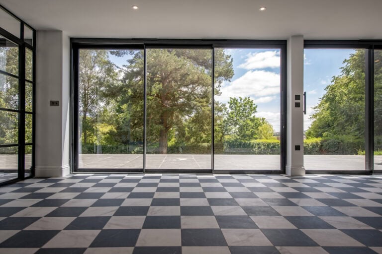 Contemporary bi-folding doors opening to a scenic outdoor view at Stumperlowe Hall, showcasing sleek design and large glass panels for natural light.