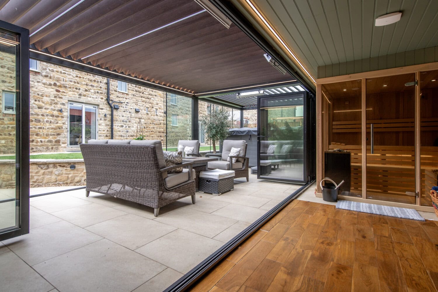 Contemporary garden room featuring large bi-folding doors opening to outdoor seating area, ideal for indoor-outdoor living and entertaining.