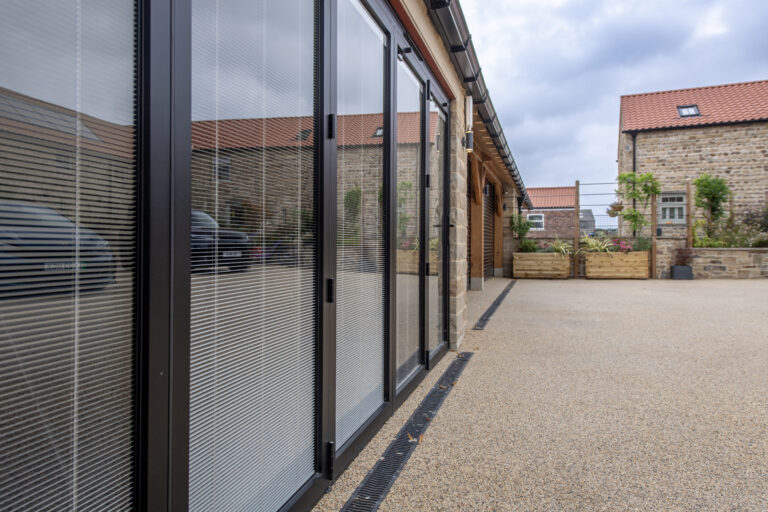 Modern bi-folding doors with glass panels opening to an outdoor patio, enhancing indoor-outdoor living spaces.