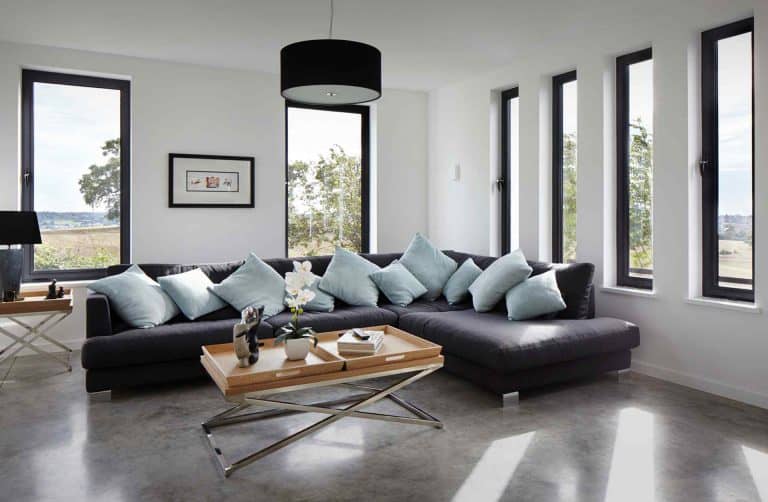 Comfortable corner group sofa in bright living room with aluminium windows.