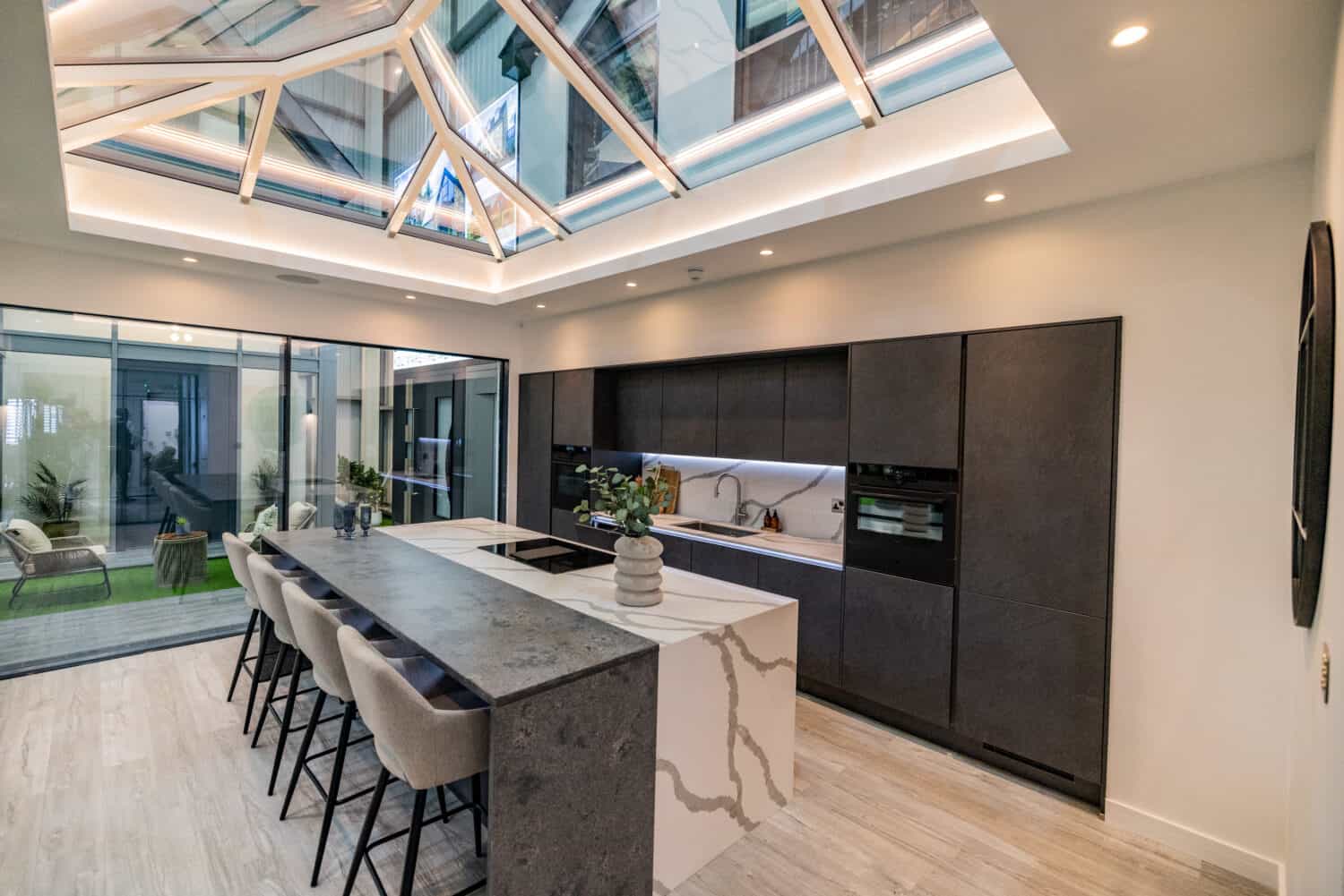 Modern black kitchen with an island featuring 2 panel sliding doors in a showroom