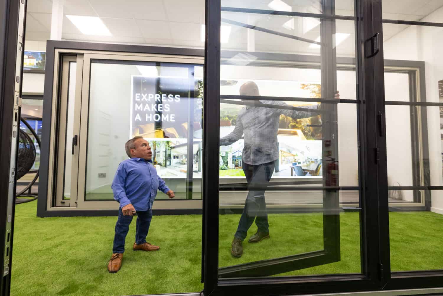 Two men having a conversation by aluminium bifold doors in a showroom