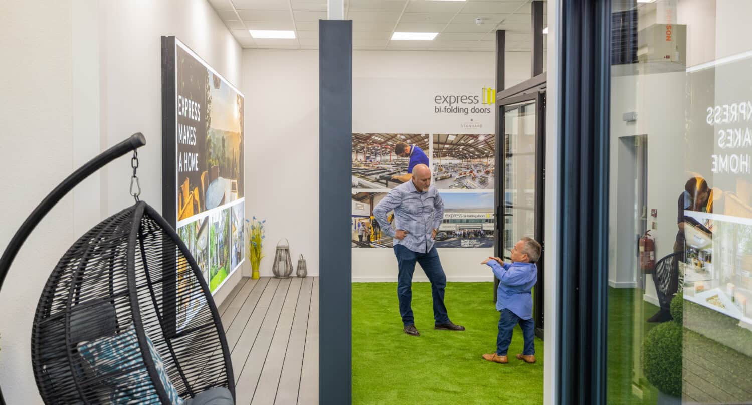 Two men having a conversation by aluminium bifold doors in a showroom