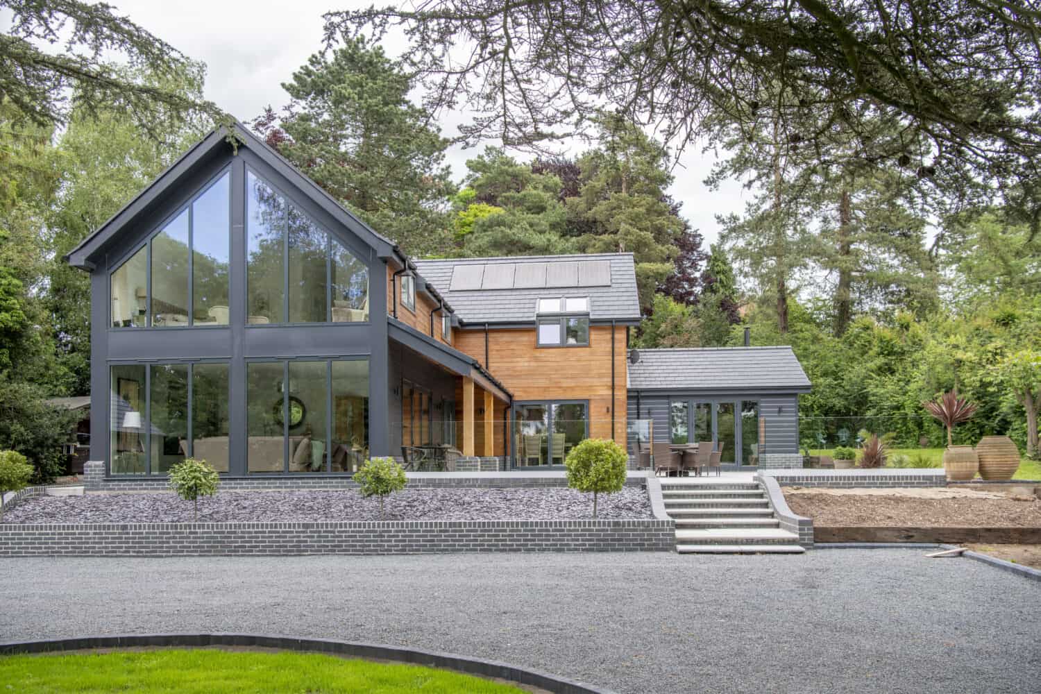 Impressive modern home featuring black aluminium curtain walling and bi folding doors linking the indoor and outdoor spaces