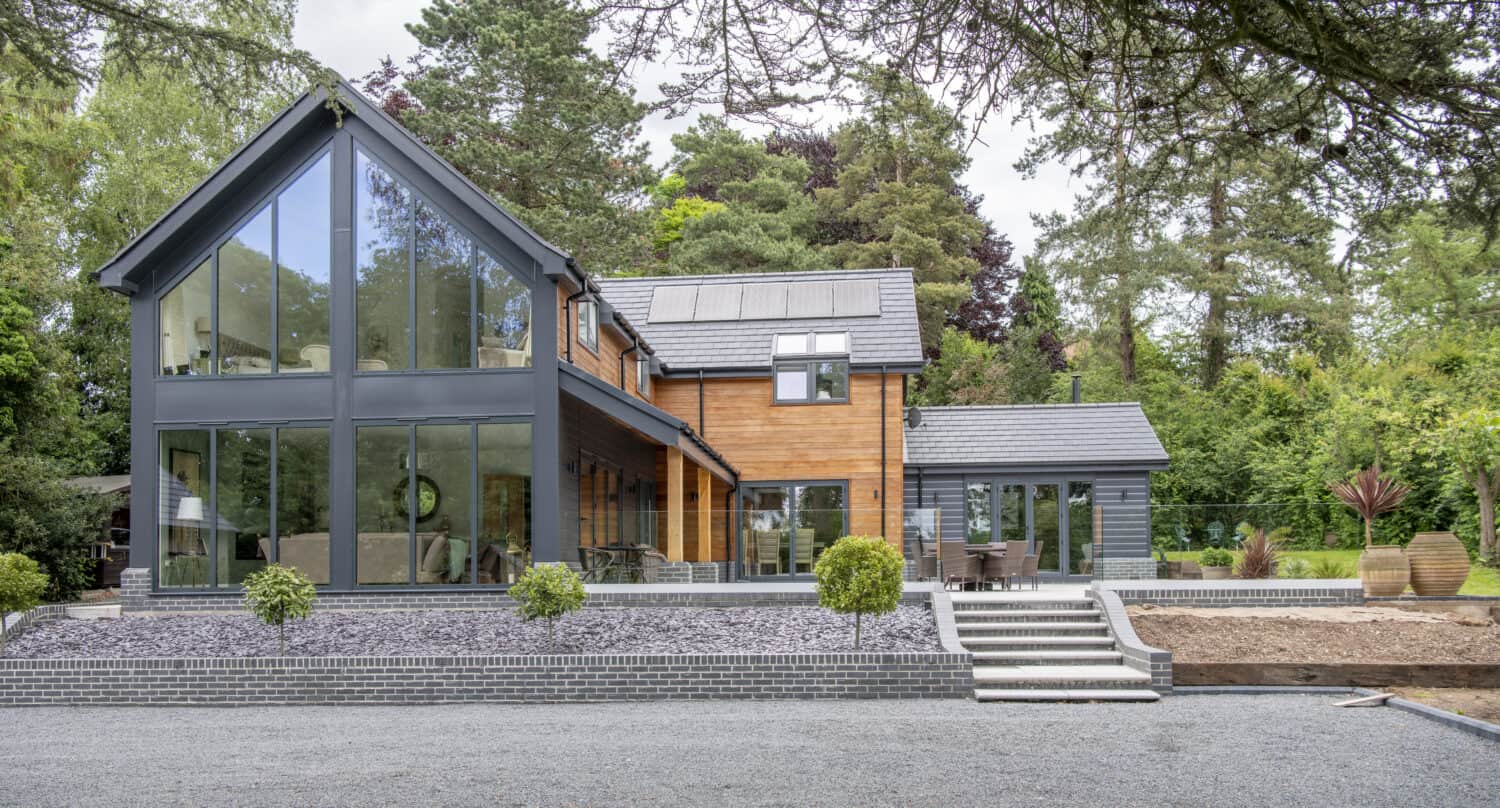 Impressive modern home featuring black aluminium curtain walling and bi folding doors linking the indoor and outdoor spaces