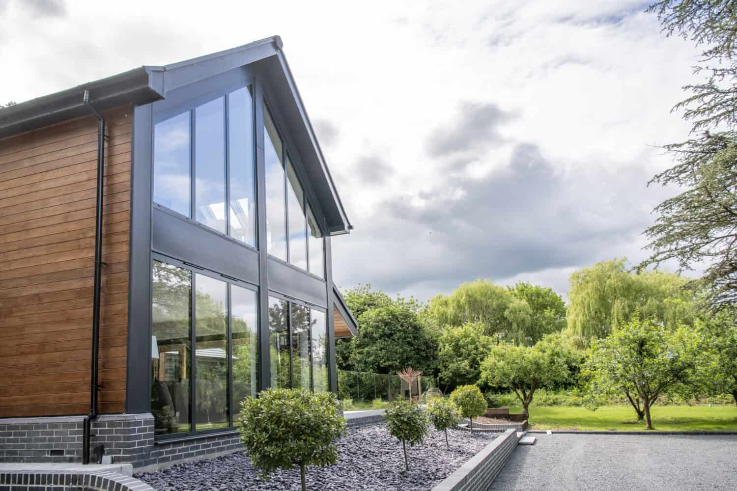 Side view of a house featuring glass curtain walling and a glass balustrade in the patio area