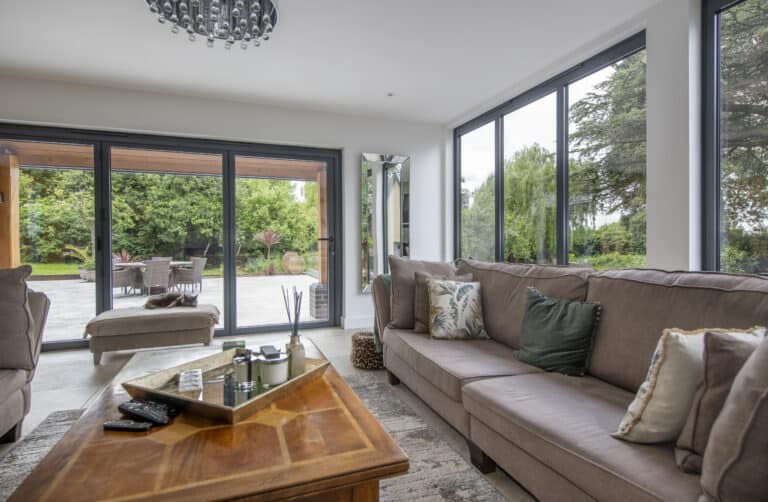 Modern living room space featuring grey aluminium bifold doors connecting the outdoor patio