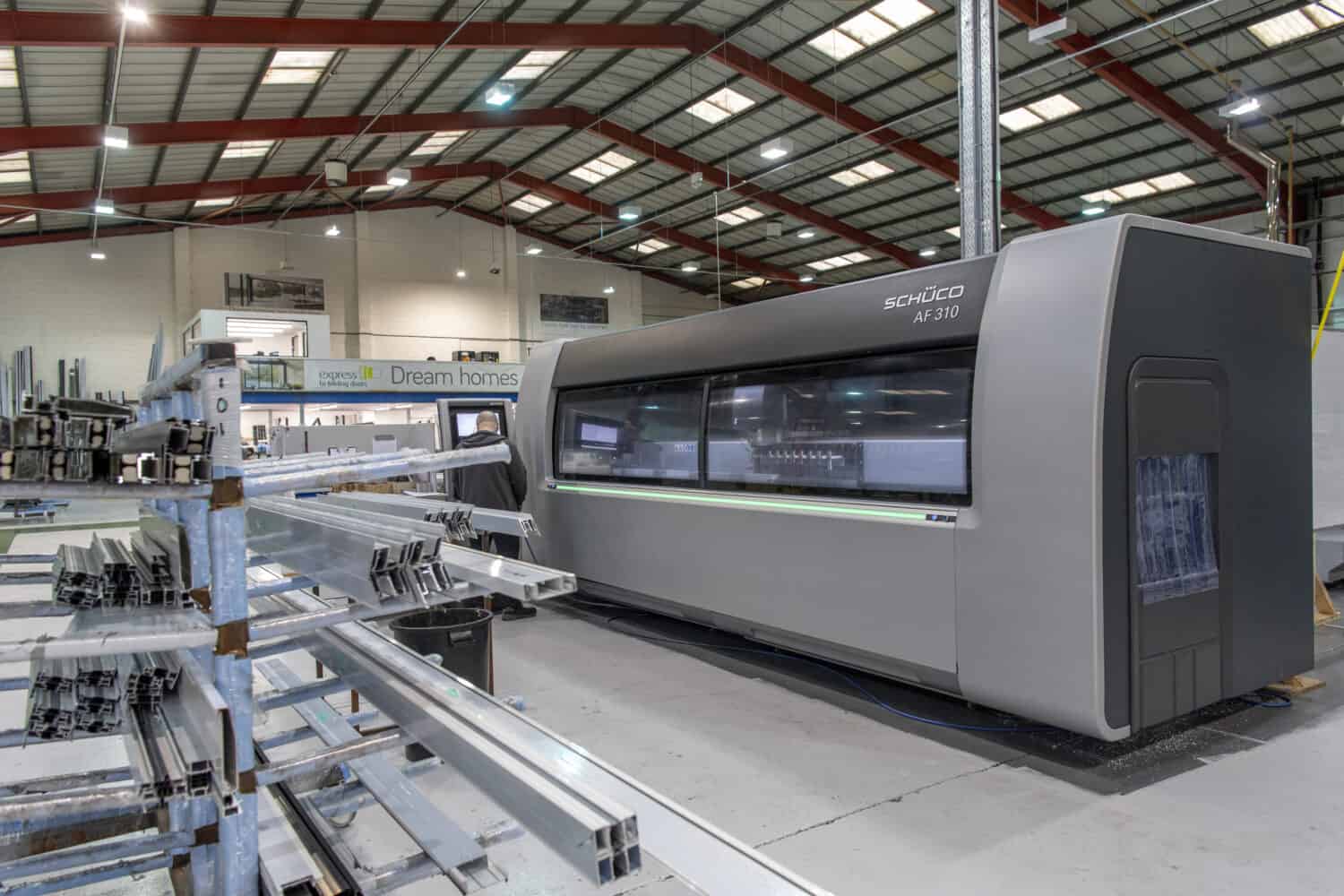 Man operating a machine in a bifold and sliding doors manufacturing warehouse