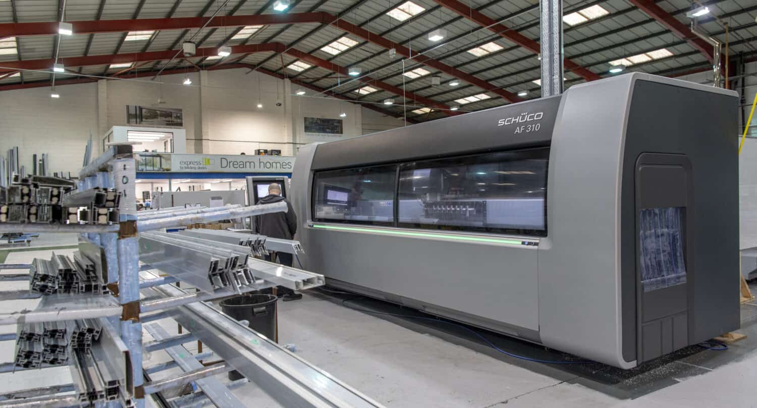 Man operating a machine in a bifold and sliding doors manufacturing warehouse