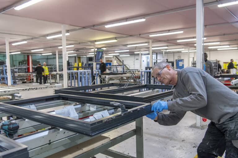 Technician working on an aluminium window in a manufacturing warehouse