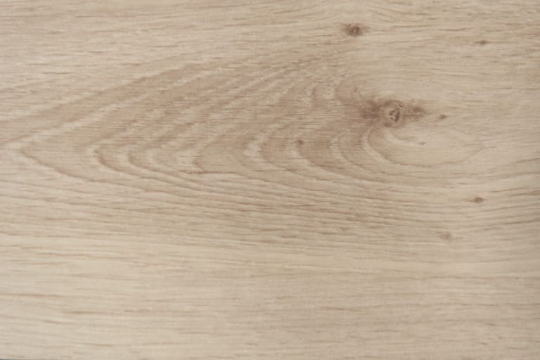 Close-up of a light-colored wooden surface, often used for front doors, showing natural grain patterns and knots.