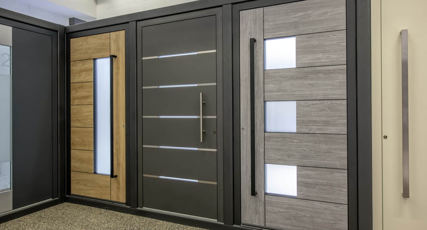 Three modern front doors displayed side by side in a showroom, each with sleek designs, vertical handles, and decorative glass panels—perfectly complementing spaces with sliding doors or glass roofing for a contemporary touch.