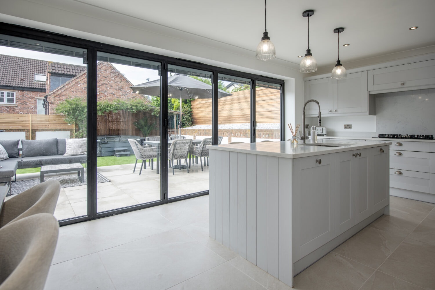 Modern kitchen extension with black aluminium bifold doors and patio dining area