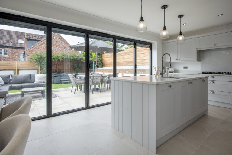 Modern kitchen extension with black aluminium bifold doors and patio dining area
