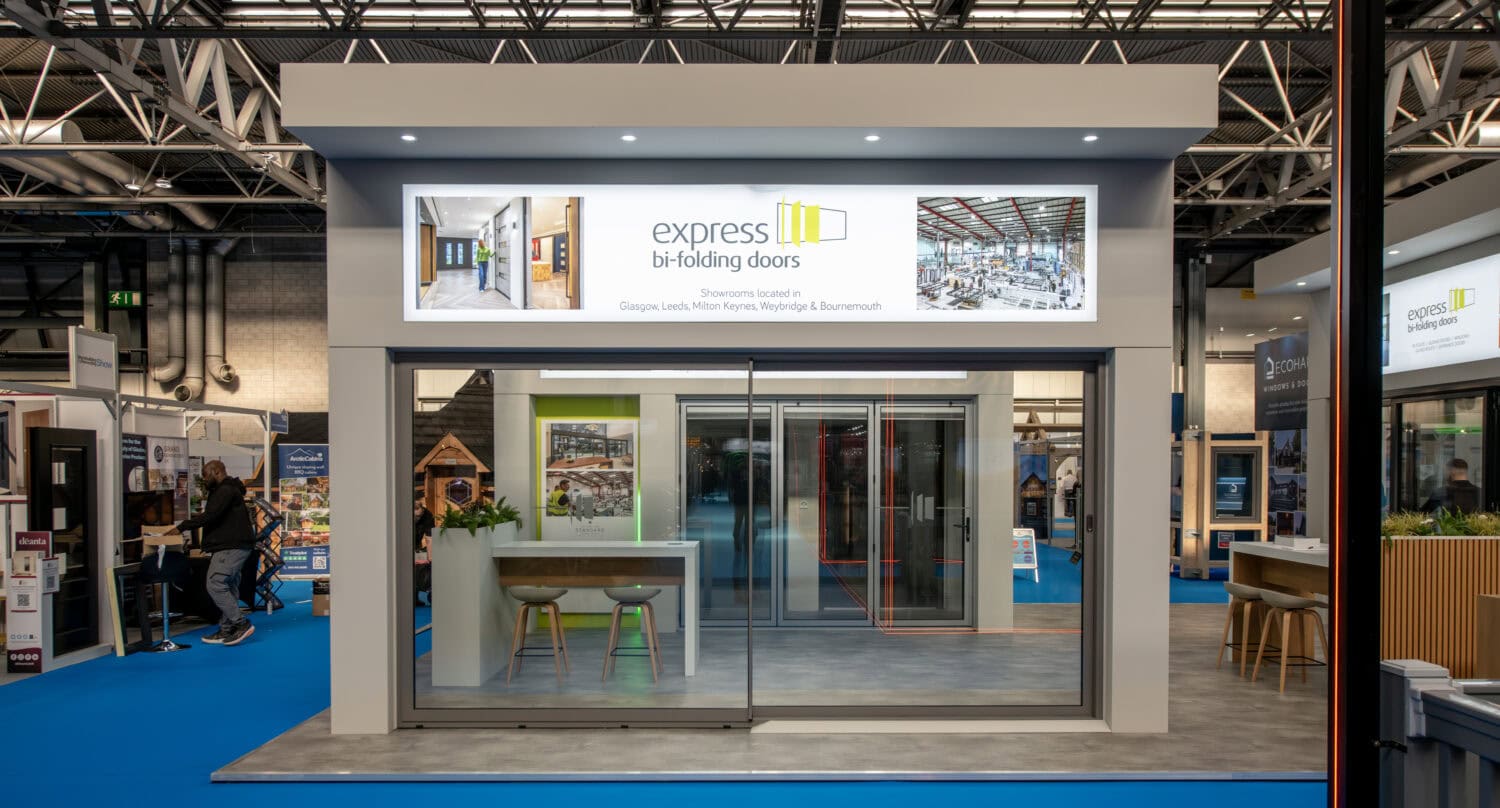 Modern exhibition stand showcasing Express Bi-Folding Doors at upcoming trade show, highlighting sleek glass doors and innovative design for home and commercial use.