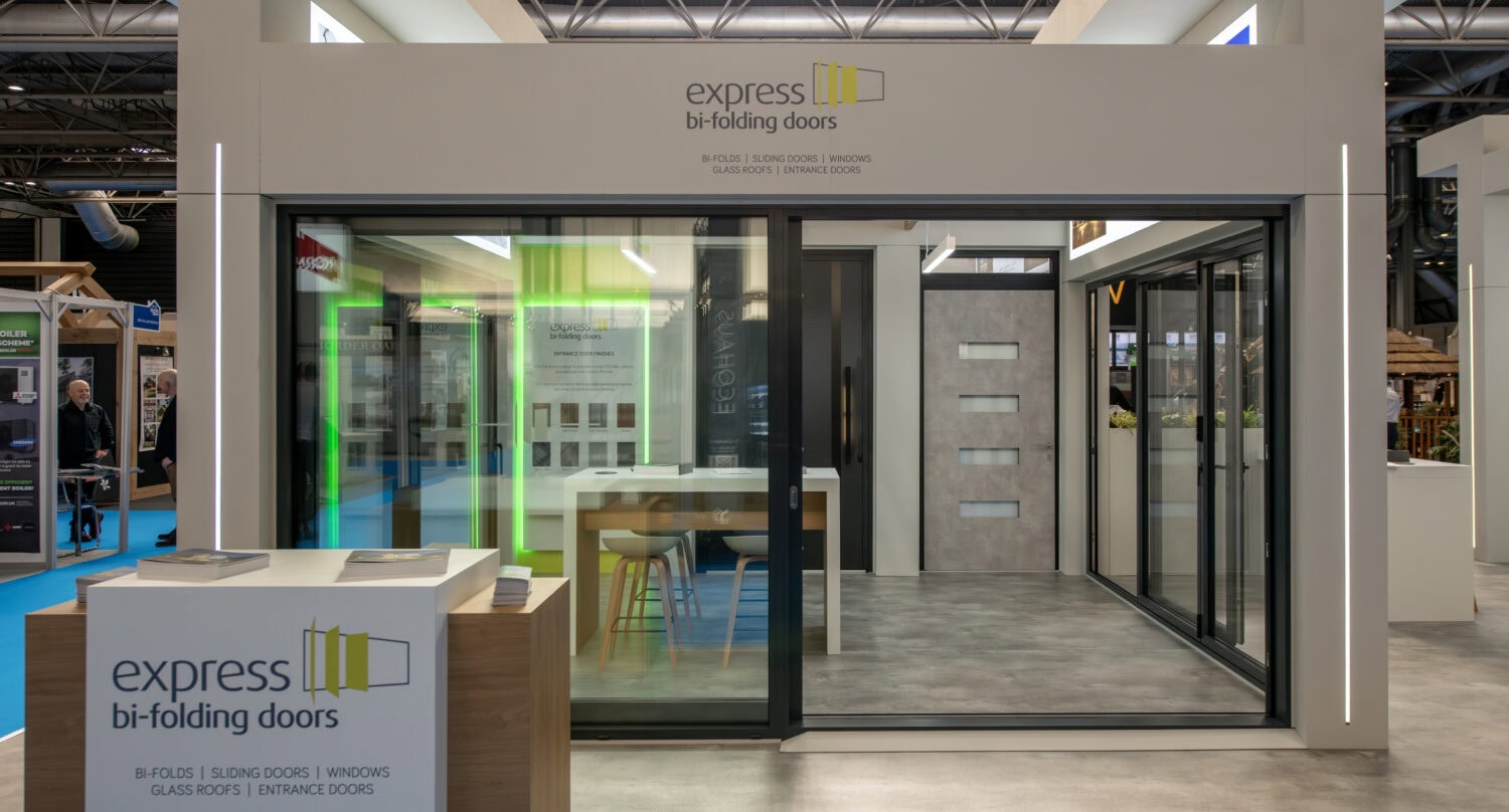 An elegant display of Express Bi-Folding Doors at an upcoming event, showcasing sleek black frames and seamless folding mechanisms designed for stylish indoor-outdoor transitions.