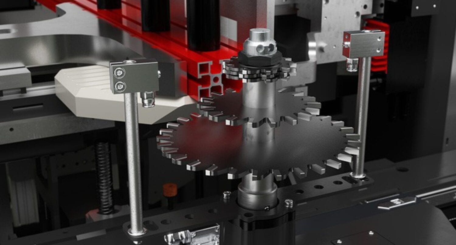 Close-up of a mechanical system featuring two interlocking metal gears, surrounded by sensors and metal components in an industrial setting with red and black structural elements—ideal for facilities with glass roofing or bespoke glass solutions.