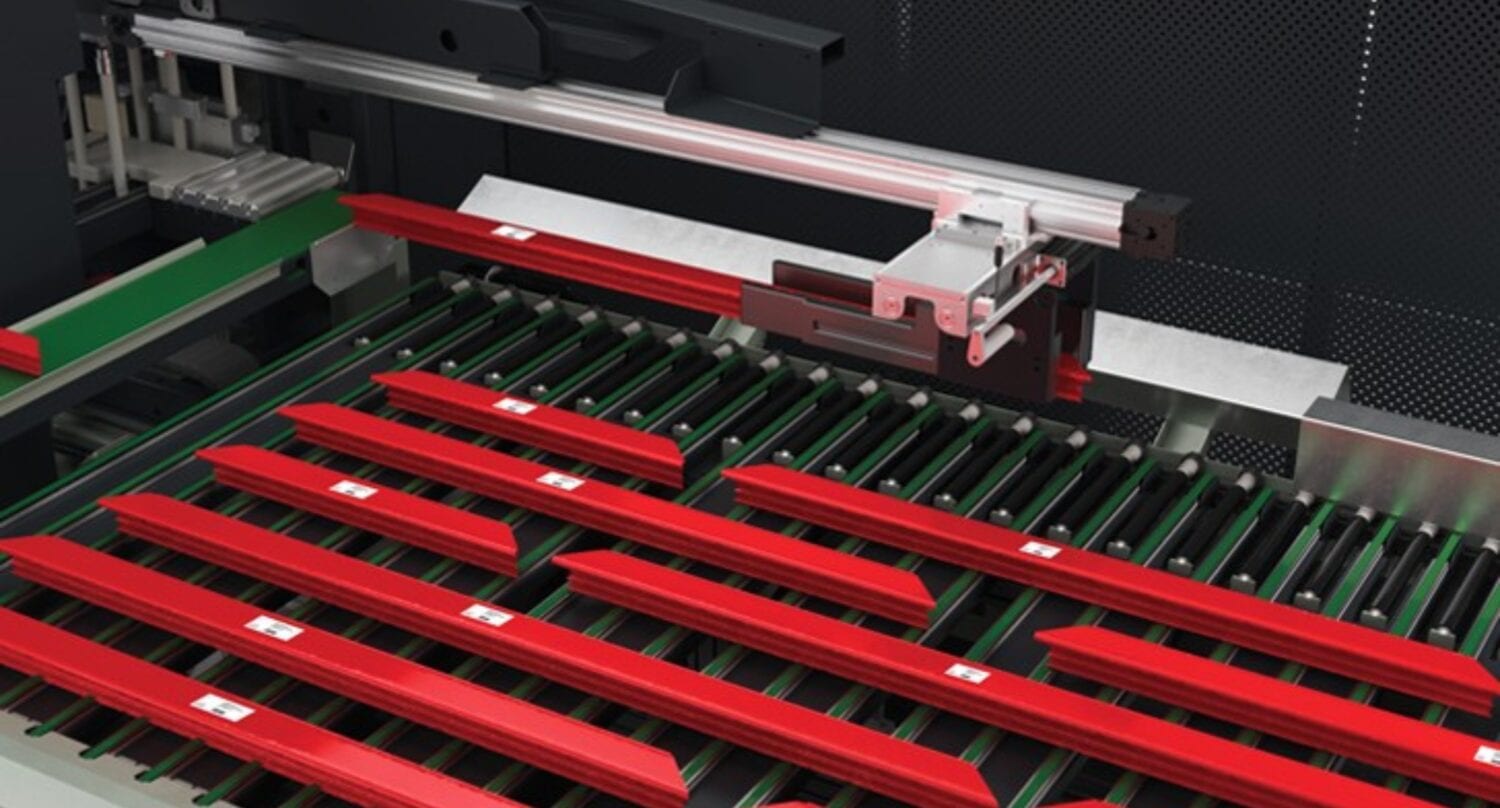 A machine with a mechanical arm organizes or inspects multiple red, rectangular objects on a green conveyor system, supporting the production of bespoke glass solutions or front doors in an industrial setting.
