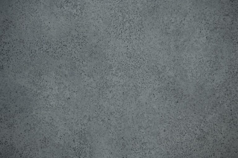 A close-up of a textured gray concrete surface with small dark speckles scattered throughout, ideal for modern spaces featuring sliding doors or front doors.