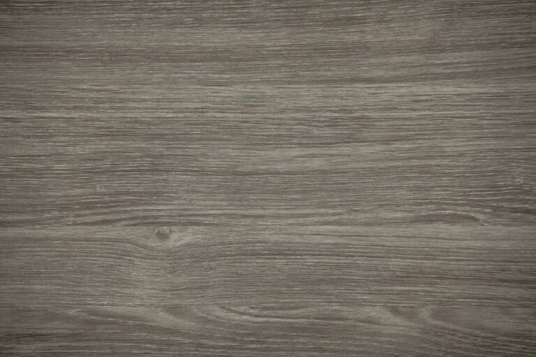 A close-up view of a wooden surface featuring subtle grain patterns and natural knots, with a muted, grayish-brown color and matte finish—perfect for bifold doors or stylish front doors.