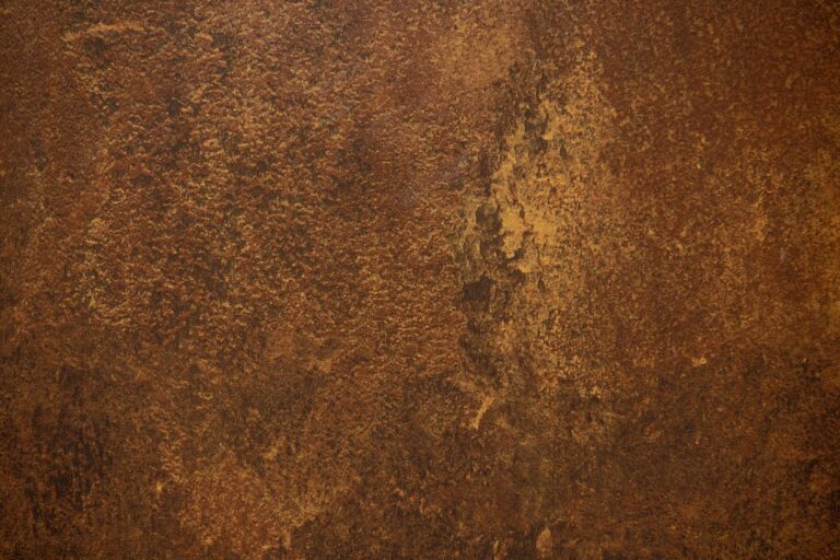A close-up of a rusty, textured metal surface with various shades of brown, orange, and yellow creates an uneven, mottled appearance—perfect inspiration for bespoke glass solutions or unique bifold doors designs.