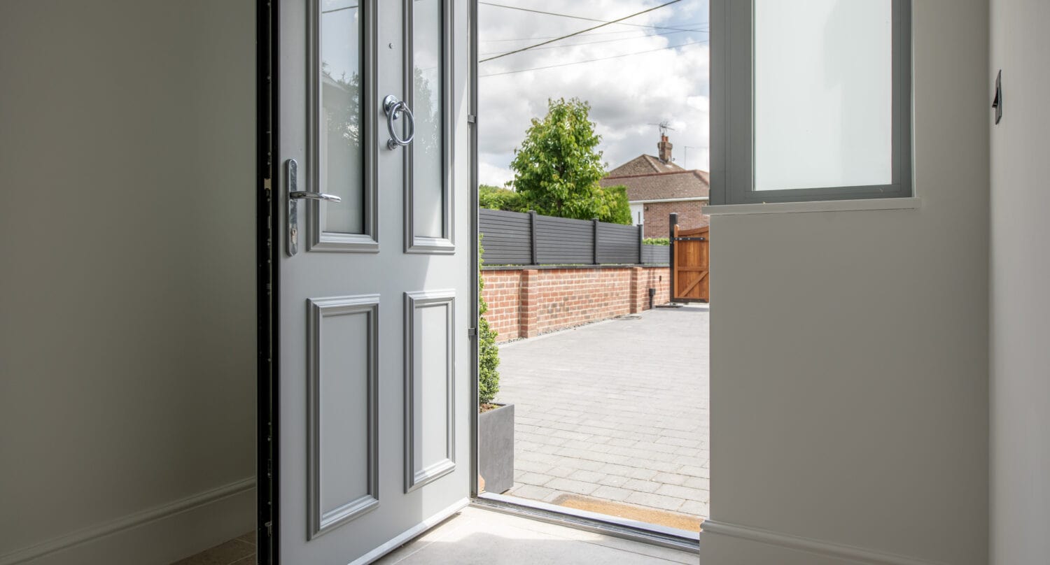An image showcasing a stylish, grey bi-folding door opening to an outdoor patio in Kent, highlighting the seamless indoor-outdoor transition and contemporary design.