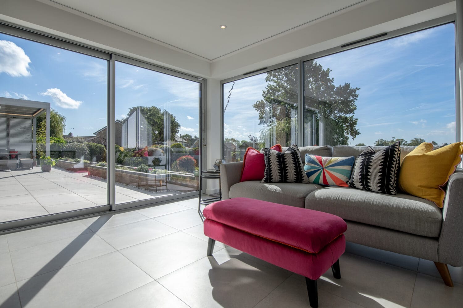 Bi-folding doors opening to a bright conservatory in Firs Drive, Harrogate, showcasing seamless indoor-outdoor living with large glass panels and aluminium frames.
