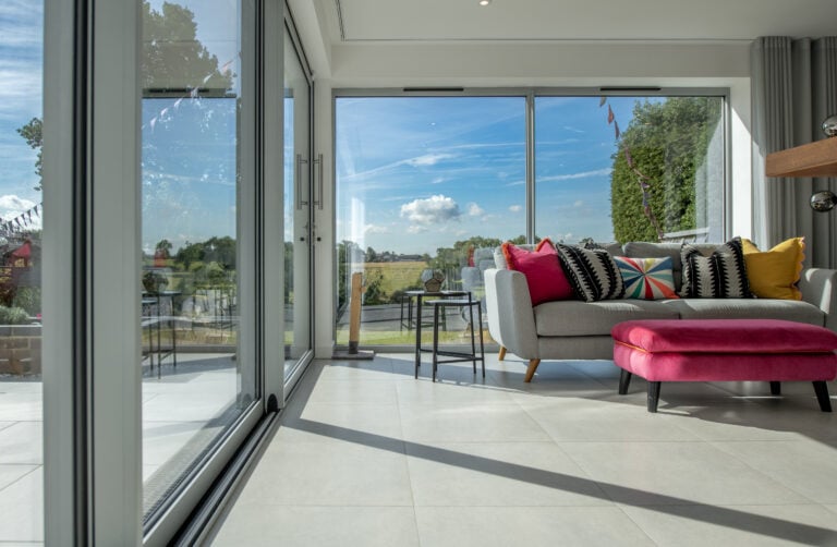 Bright living room with large bi-folding doors opening to a garden, showcasing stylish indoor-outdoor living in Harrogate. Perfect for enhancing natural light and space.
