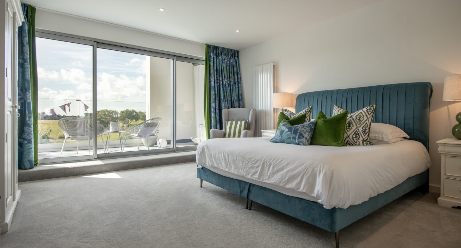 Bright and spacious bedroom featuring elegant bi-fold doors that provide seamless access to the outdoor balcony, enhancing natural light and ventilation. Perfect for stylish, energy-efficient home upg.