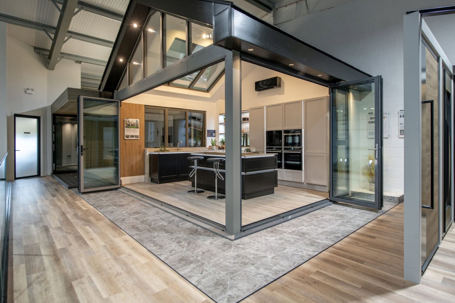 High-quality bi-folding doors opening to a stylish kitchen, showcasing seamless indoor-outdoor living in a Glasgow showroom setting.