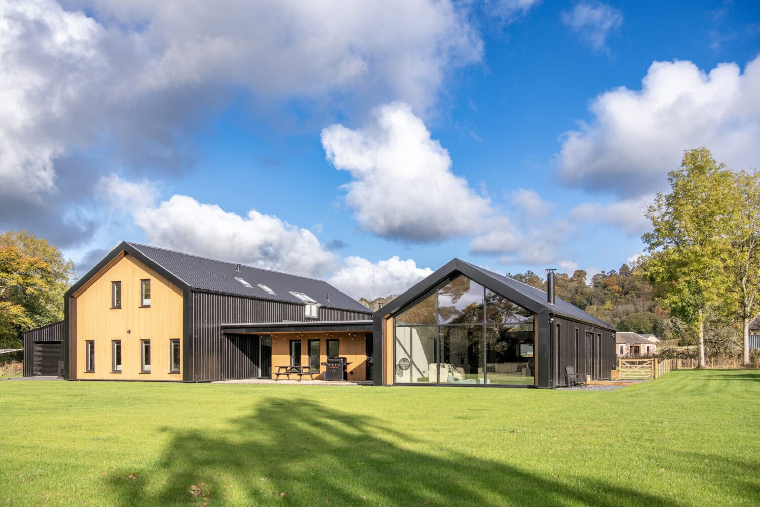 High-quality bi-folding doors at Orchard Farm, Crossford, showcasing seamless indoor-outdoor living with large glass panels and sleek black frames.
