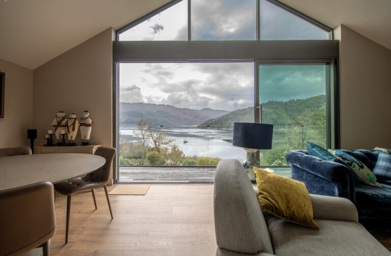 Elegant bi-folding doors opening to scenic lake views at Norse Lodge, Helensburgh, showcasing modern design and seamless indoor-outdoor living.