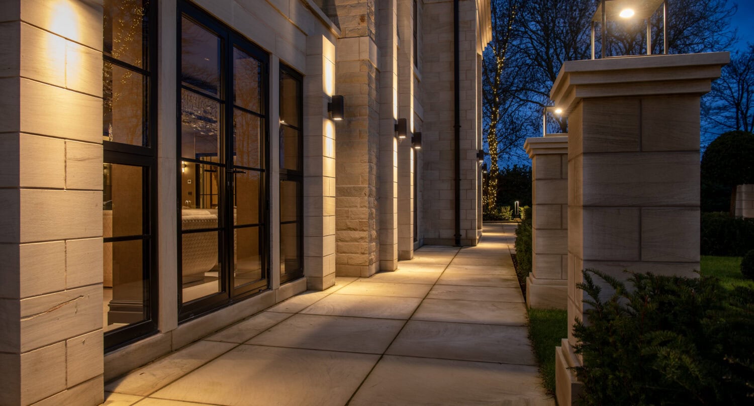 Elegant steel-look bifold doors opening to a stylish outdoor patio at dusk.