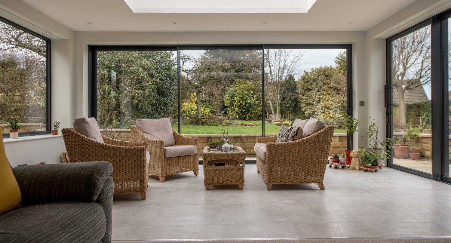 Large glass bi-folding doors at Chapel Grove offering seamless indoor-outdoor living with panoramic garden views and natural light.